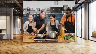 Portrait of female chef frying meat during cooking class with diverse group of people in kitchen interior Wall mural