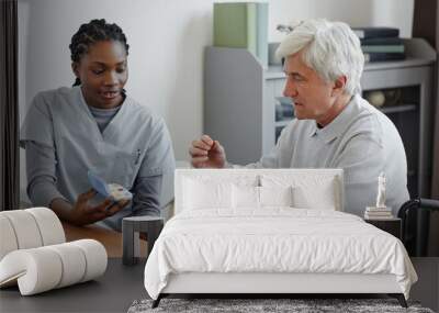 Portrait of female nurse explaining medicine schedule to senior man in retirement home Wall mural