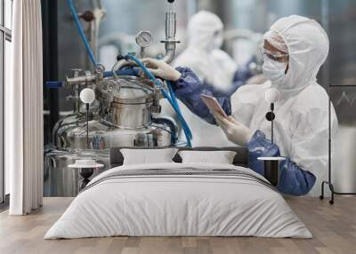 Portrait of female worker wearing protective suit while operating equipment at modern chemical plant, copy space Wall mural