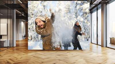 Portrait of happy family enjoying snowball fight in beautiful winter forest, focus on bearded man in foreground, copy space Wall mural