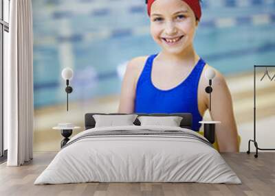 Portrait of happy little girl standing in swimwear and holding board, she is going to learn to swim Wall mural