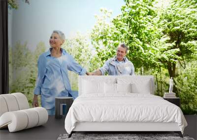 Portrait of happy senior woman leading husband by hand while enjoying walk in Summer park, copy space Wall mural