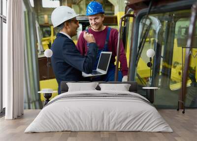 Portrait of industrial worker smiling happily while talking to supervisor using laptop, copy space Wall mural