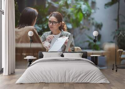 Portrait of modern businesswoman pointing at contract during meeting in outdoor cafe terrace, copy space Wall mural