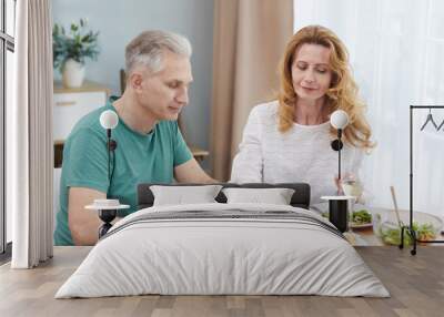 Portrait of modern mature couple holding hands while enjoying healthy dinner together at home, copy space Wall mural