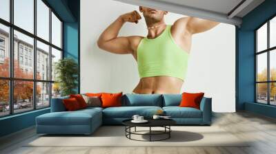 Portrait of muscular non binary man posing against white in studio wearing neon green crop top Wall mural