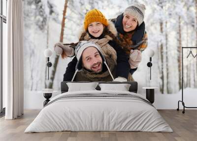 Portrait of playful happy family in winter forest looking at camera and smiling, copy space Wall mural