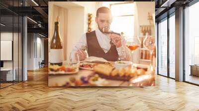 Portrait of professional sommelier smelling wine during tasting session in winery lit by sunlight, copy space Wall mural