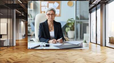 Portrait of senior woman as female boss sitting at workplace in office and looking at camera, copy space Wall mural