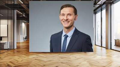 Portrait of smiling adult businessman looking at camera against plain grey background, copy space Wall mural