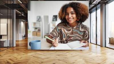 Portrait of smiling African-American girl studying at home and smiling at camera, copy space Wall mural