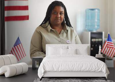 Portrait of smiling African-American woman working at at polling station on election day and registering voters, copy space Wall mural