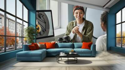 Portrait of smiling female photographer collaborating with colleague or client while discussing images in studio Wall mural