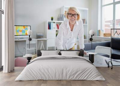 Portrait of smiling mature woman looking at camera while working with designs in modern office, copy space Wall mural