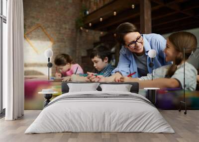 Portrait of smiling young woman working with kids in art class, copy space Wall mural