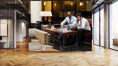 Portrait of two business people discussing deal in hotel lounge, copy space Wall mural