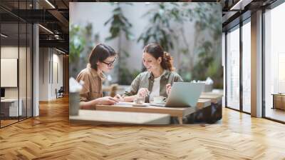 Portrait of two cheerful young omen enjoying work in beautiful outdoor cafe, copy space Wall mural