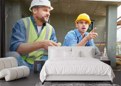 portrait of two construction workers taking break on site eating lunch out of plastic containers out Wall mural