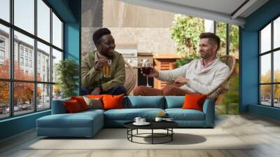 Portrait of two contemporary men enjoying wine while relaxing in lounge chairs at outdoor terrace, copy space Wall mural