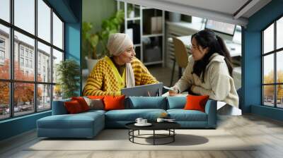 Portrait of two creative young women collaborating in business meeting while enjoying work in office Wall mural