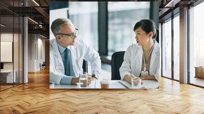 Portrait of two doctors sitting at meeting table in conference room during medical seminar Wall mural