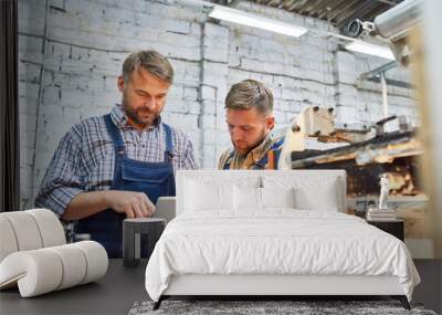 portrait of two factory workers using modern machine at factory operating it via digital tablet, cop Wall mural