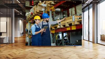 Portrait of two modern factory workers, man and woman, wearing hardhats doing inventory standing by shelves in warehouse, copy space Wall mural