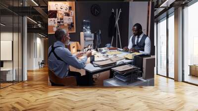 Portrait of two police detectives sitting at desk in office and studying case investigations, copy space Wall mural