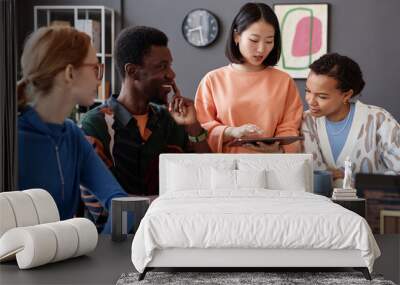 Portrait of young Asian woman as manager instructing diverse team of colleagues in office and using digital tablet Wall mural