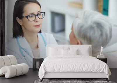 Portrait of young female doctor examining senior woman during consultation in medical clinic Wall mural