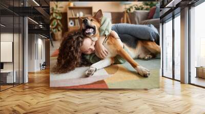 Portrait of young woman playing with happy dog fooling around on floor at home, copy space Wall mural