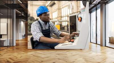 Portrait shot of highly professional worker wearing checked shirt and overall operating machine at production department of modern plant Wall mural