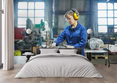 Potrait of modern female worker cutting metal at industrial plant or garage, copy space Wall mural