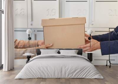 Side view close up at two people handing cardboard box while standing by self storage unit or postal boxes, copy space Wall mural