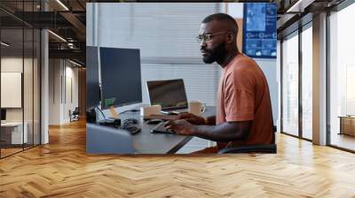 Side view of black software engineer using computer in high technology office, data systems and programming Wall mural