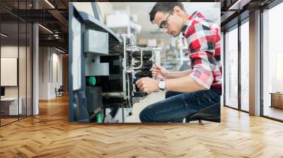 Side view of casual man working with modern printing equipment in typography office Wall mural