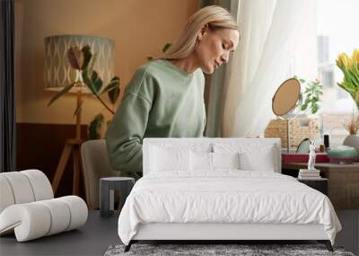 Side view portrait of blonde adult woman doing manicure at vanity table by window copy space Wall mural