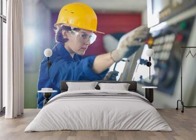 Side view portrait of female worker pushing STOP button while operating machine units at metal production plant, copy space Wall mural