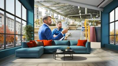 Side view portrait of handsome mature businessman touring modern factory inspecting quality of production, assisted with young workman, copy space Wall mural