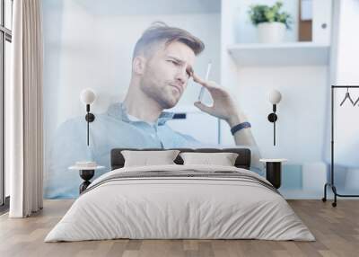 Side view portrait of handsome young man frowning in thought while working in office, copy space Wall mural