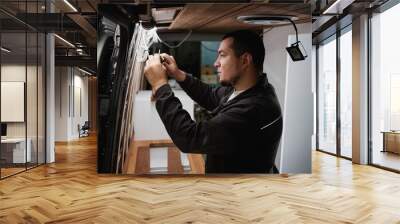 Side view portrait of man building camper van and installing wires for electrics Wall mural