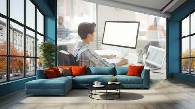 Side view portrait of modern young woman using computer in office, focus on blank white screen, copy space Wall mural