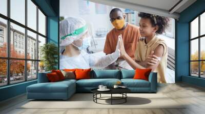 Side view portrait of smiling African-American boy high five nurse after covid vaccination in clinic or hospital, copy space Wall mural