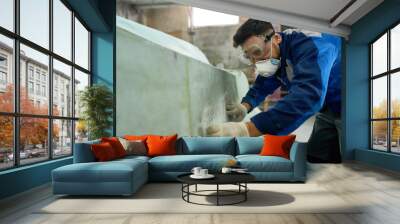 Side view portrait of worker wearing protective mask repairing boat while working in yacht workshop, copy space Wall mural