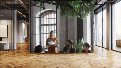 Side view view at multi-ethnic group of business people collaborating at meeting table in trendy office interior, copy space Wall mural