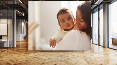 Smiling loving young African mom with curly hair standing in room and holding adorable baby boy with chubby cheeks Wall mural