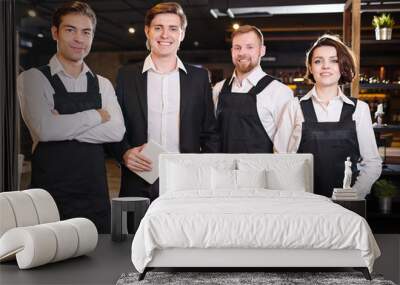 Team of restaurant professionals in ahead of manager standing in line and smiling at camera Wall mural