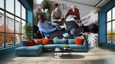 Top view at large diverse group of business people sitting at table during briefing meeting in office Wall mural