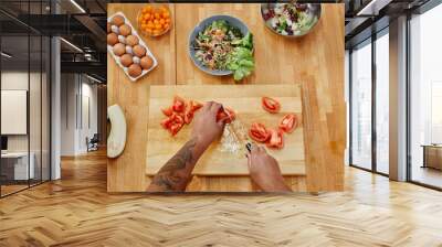 Top view close up of female hands cutting vegetables while cooking on wooden table with assorted ingredients, copy space Wall mural