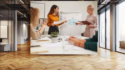 Two beautiful business colleagues working together at meeting making report, horizontal point of view shot Wall mural